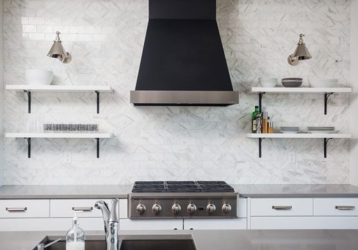 optlachancestovewall Modern kitchen with stainless steel appliances, marble backsplash, and open shelving displaying dishware and kitchen tools.